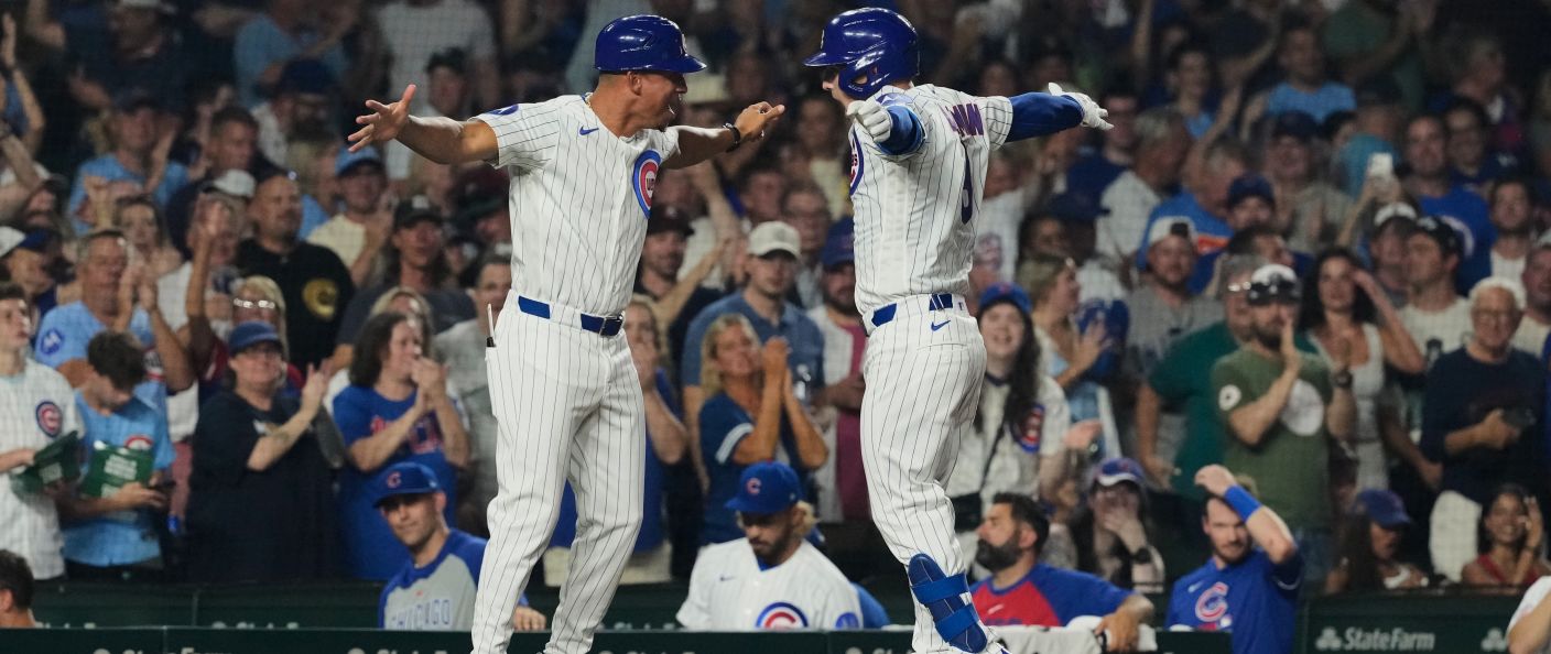 Le public de Wrigley Field debout pendant que deux joueurs des Cubs célèbrent un home run, à Chicago.