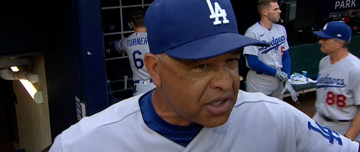Le manager des Dodgers Dave Roberts dans l'abri, ses joueurs en arrière-plan.