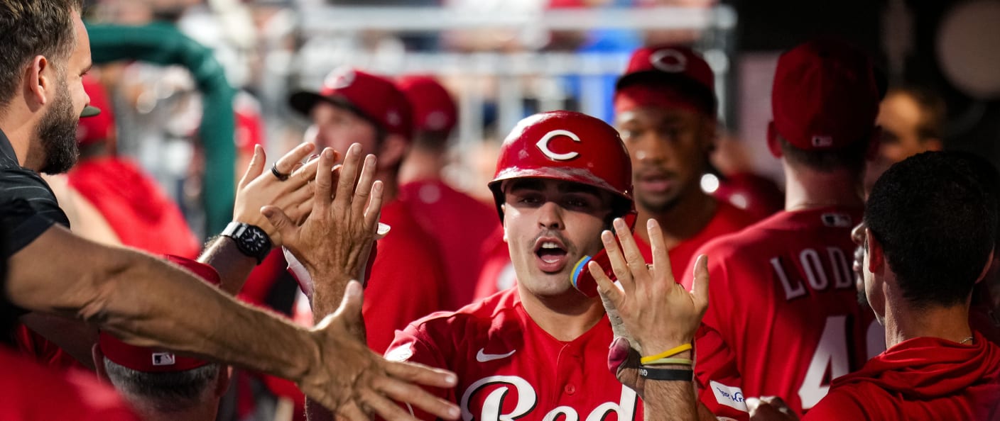 Un frappeur des Reds félicité par ses coéquipiers dans l'abri après un coup de circuit.