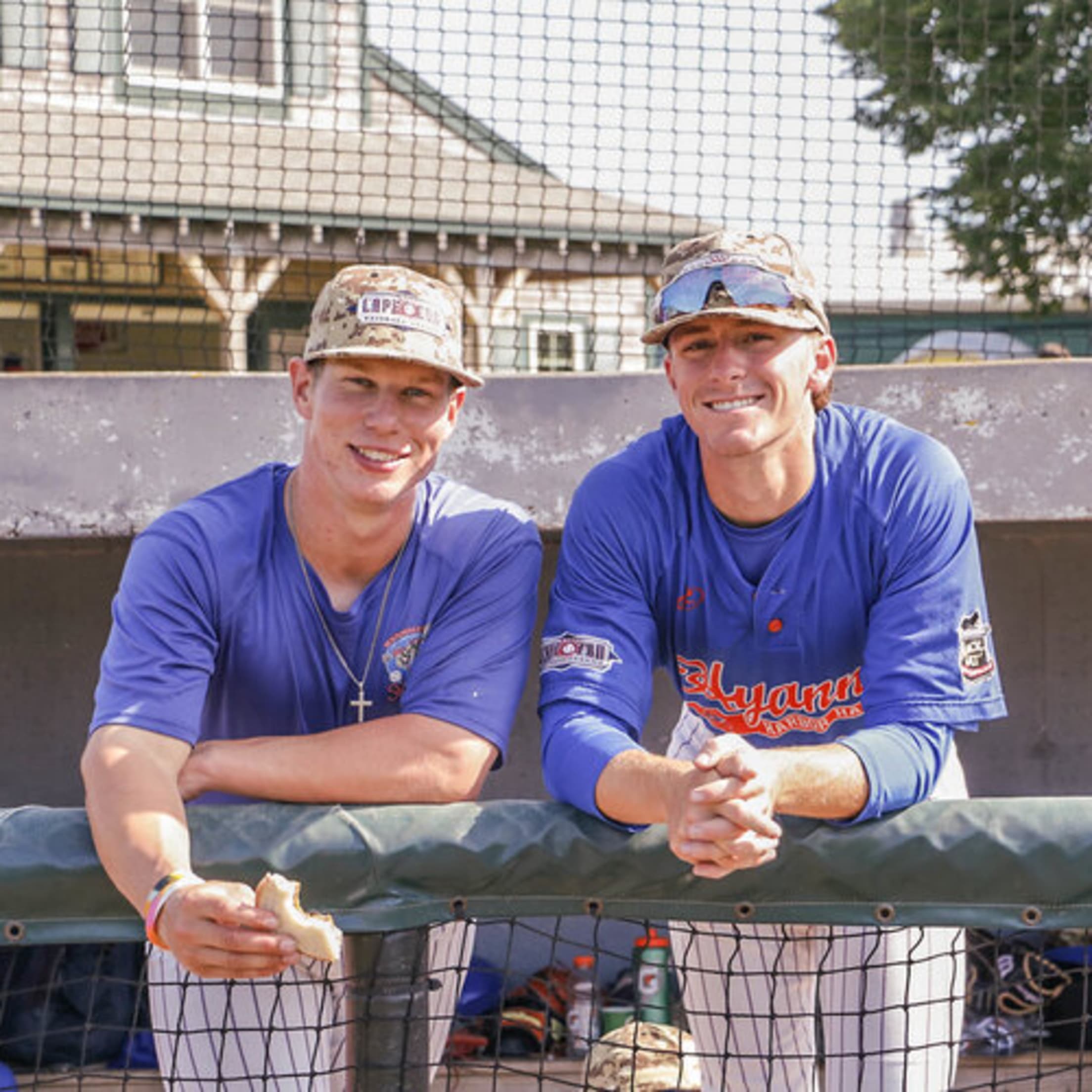 Two Hyannis players smile from the dugout.